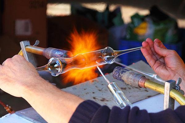 closeup of hands holding a piece of glass being fired
